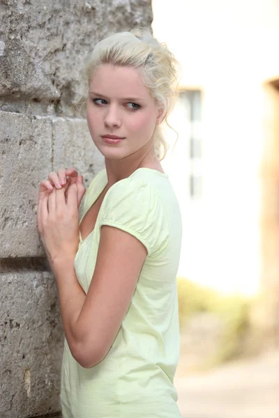 Young woman posing against a stone building — Stock Photo, Image