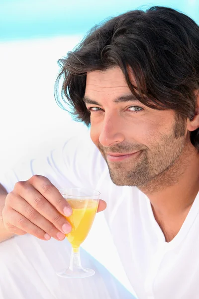 Homme aux cheveux foncés buvant du jus d'orange — Photo