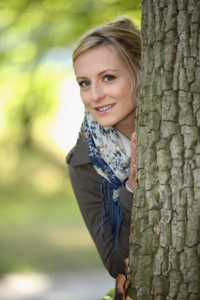 Blondine stand hinter Baum — Stockfoto