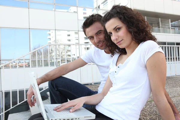 Couple sat in steps with laptop — Stock Photo, Image