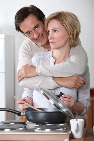 Uomo abbracciando sua moglie mentre lei sta cucinando — Foto Stock