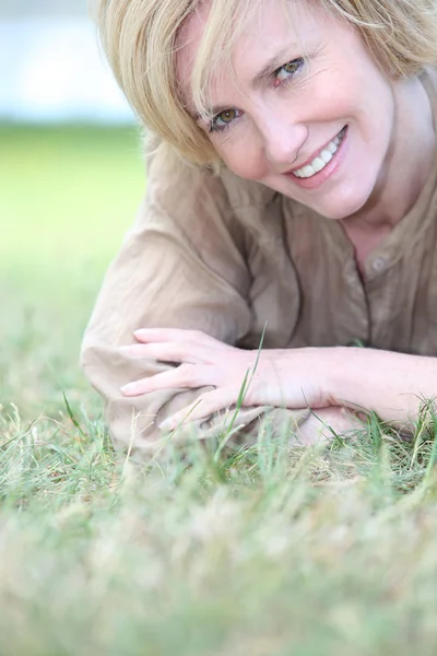 Blonde vrouw gelegd in gras — Stockfoto