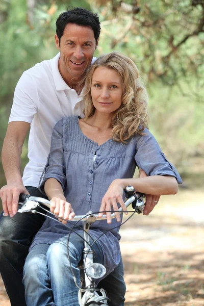 Couple riding bike in forest — Stock Photo, Image