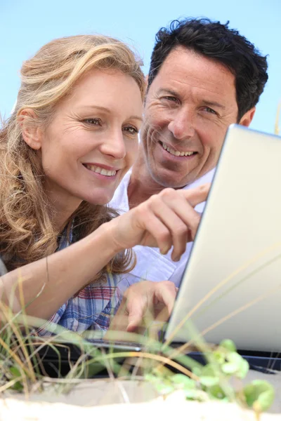 Пара смотрит на ноутбук на открытом воздухе . — стоковое фото