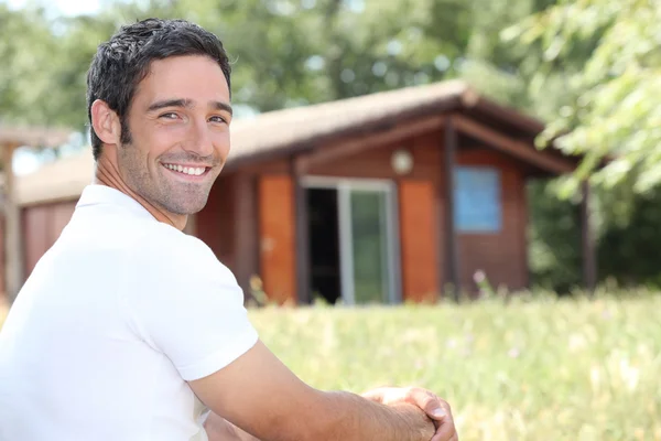 Homem sorridente sentado em frente a uma cabine — Fotografia de Stock