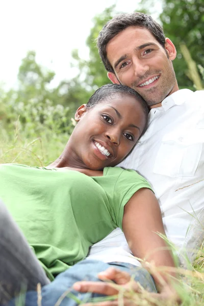 Un couple interracial allongé sur l'herbe . — Photo
