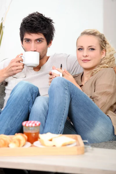 Couple prenant le petit déjeuner sur le canapé — Photo