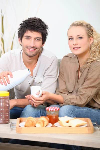 Couple eating breakfast on a sofa — Stock Photo, Image