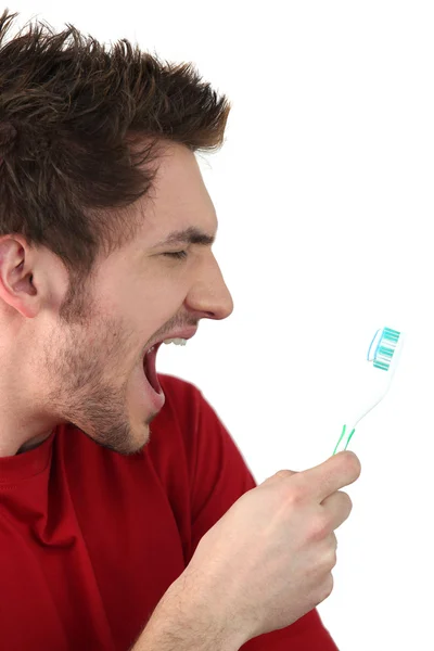 Young man shouting at his toothbrush — Stock Photo, Image
