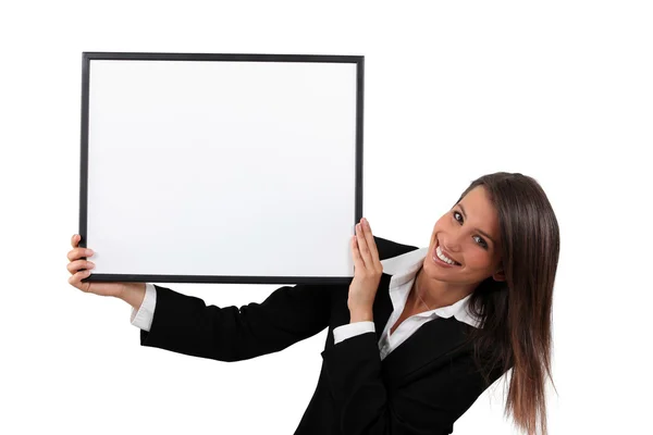 Mujer con un traje negro inteligente sosteniendo una tabla en blanco para tu imagen o para mí — Foto de Stock