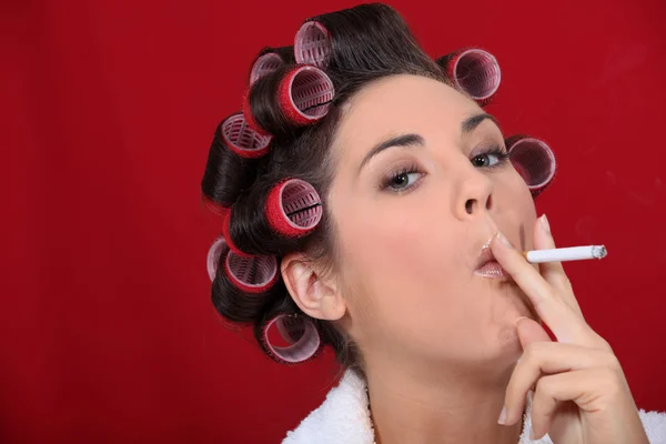 Donna con rulli per capelli fumatori — Foto Stock