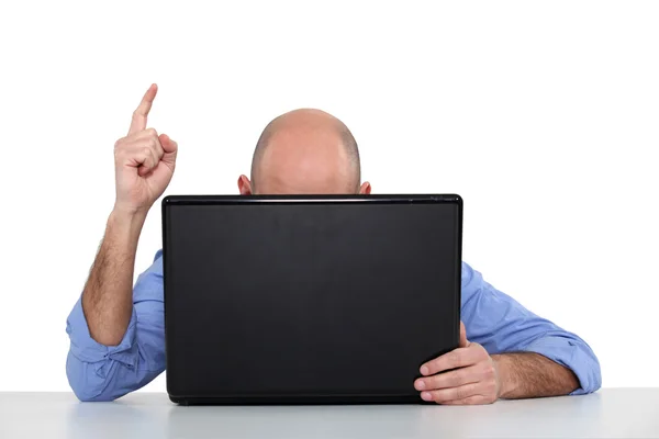 Man at a laptop pointing his finger in the air — Stock Photo, Image