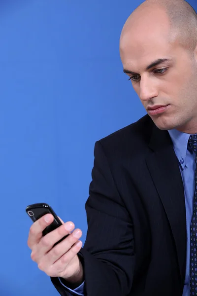 Бизнесмен смотрит на свой мобильный телефон — стоковое фото