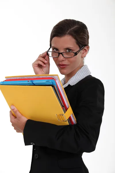 Sekretärin hält Ordner in der Hand und blickt über ihre Brille — Stockfoto