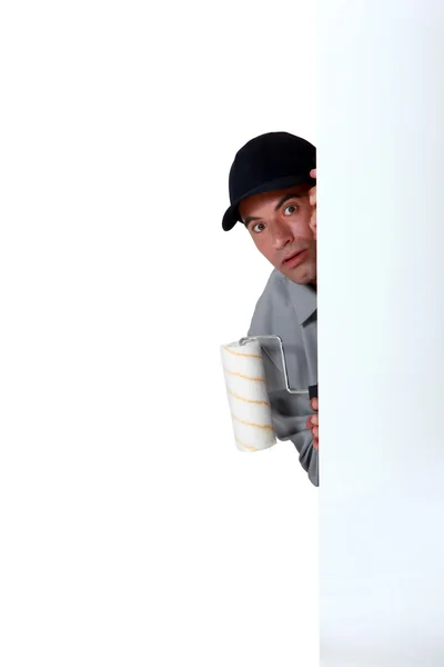A scared painter hiding behind a wall. — Stock Photo, Image