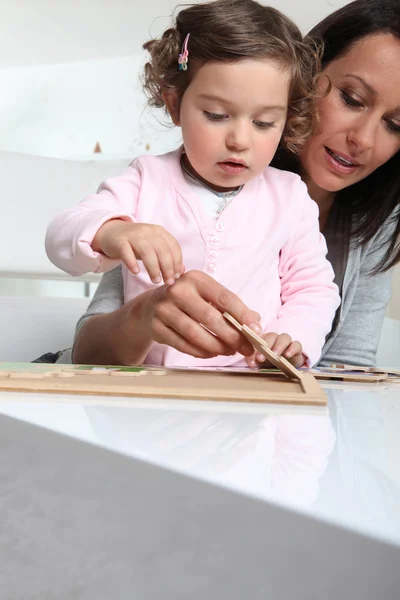 Klein meisje en nanny een puzzel maken — Stockfoto