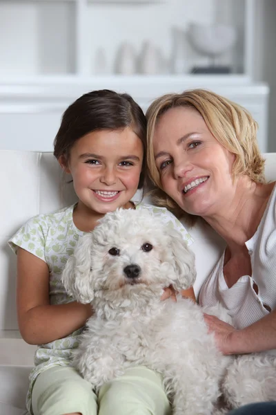 Moeder, dochter en witte hond zit in een wit woonkamer — Stockfoto