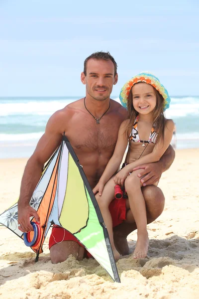 Homem em uma praia com sua filha e um papagaio — Fotografia de Stock