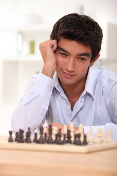 Mladý muž uvažuje o jeho další krok šachy — Stock fotografie