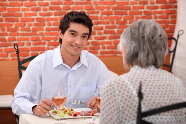 Jeune homme déjeunant avec sa grand-mère — Photo