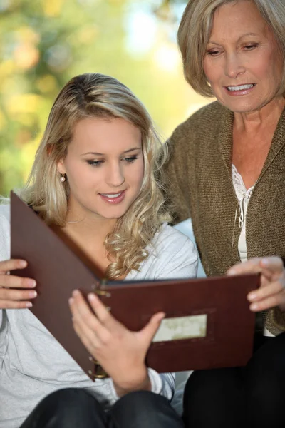 Mujer joven y su abuela mirando un álbum de fotos — Foto de Stock