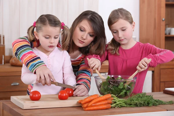 Mutter bringt ihren Töchtern das Kochen bei. — Stockfoto