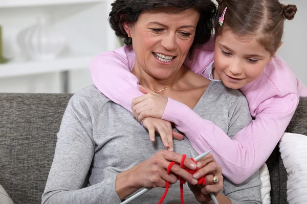 A mom showing how to knit to her daughter.