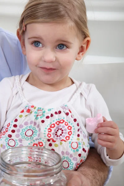 Ein kleines Mädchen isst Marshmallows. — Stockfoto