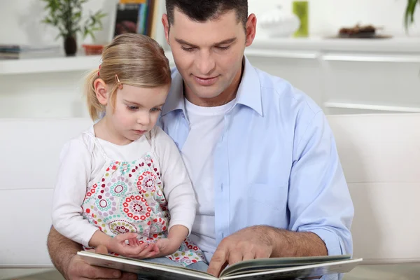 Молодой отец читает историю своей дочери — стоковое фото