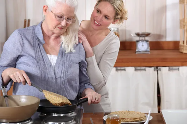Дочь помогает своей старшей матери на кухне — стоковое фото