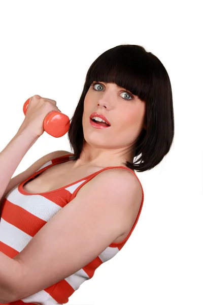 Brunette wearing striped sleeveless top lifting dumbbell — Stock Photo, Image