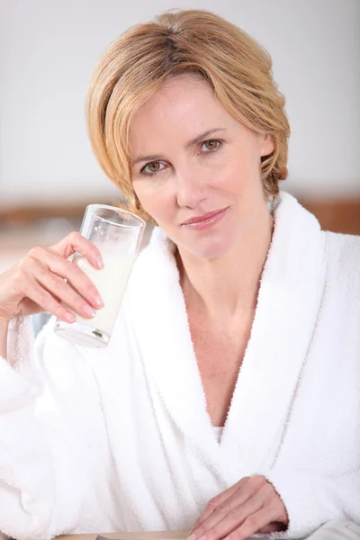 Femme blonde en peignoir blanc tenant un verre d'eau — Photo