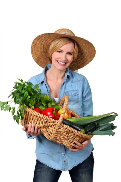 Loira carregando uma cesta cheia de legumes . — Fotografia de Stock
