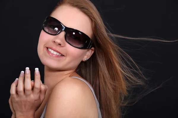 Досить усміхнена дівчина з сонцезахисними окулярами на чорному тлі — стокове фото