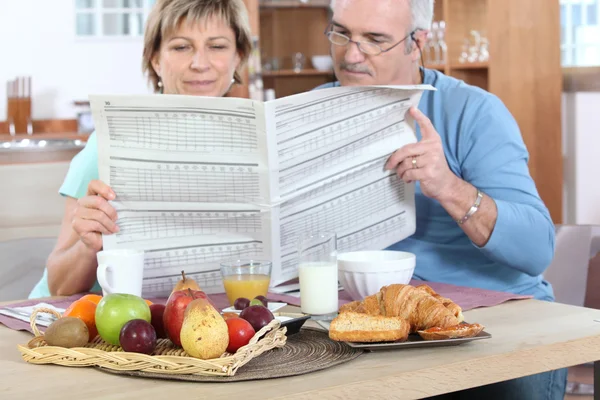 Couple reading newspaper at breakfast — Stock Photo, Image
