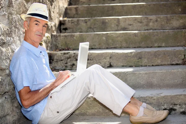 Älterer Mann macht Computer draußen am Fuße der Treppe — Stockfoto