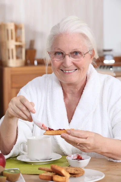 An old woman eating breakfast. — Stock Photo, Image