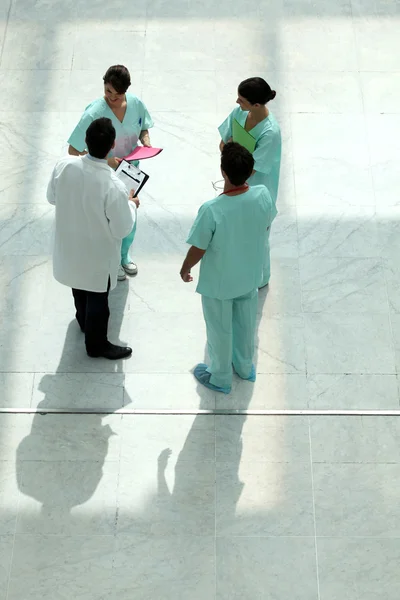 Высокий угол обзора команды медиков, болтающих в атриуме — стоковое фото
