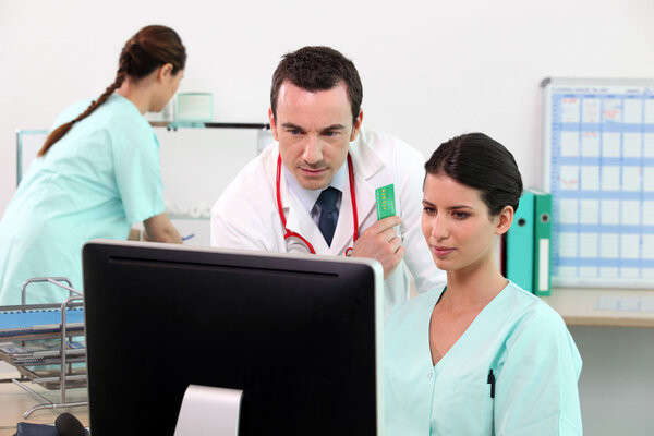 Médico y enfermera revisando detalles en una computadora — Foto de Stock