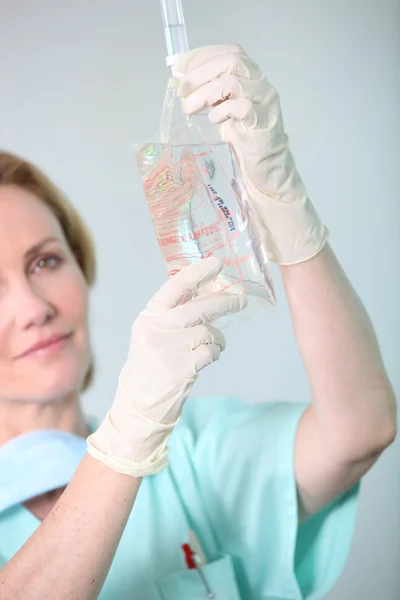 Closeup of a nurse in scrubs administering drip — Stock Photo, Image