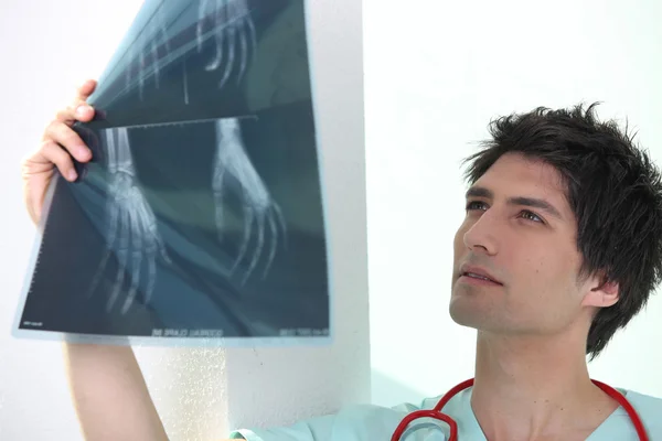 Handsome medic examining x rays of a hand — Stock Photo, Image