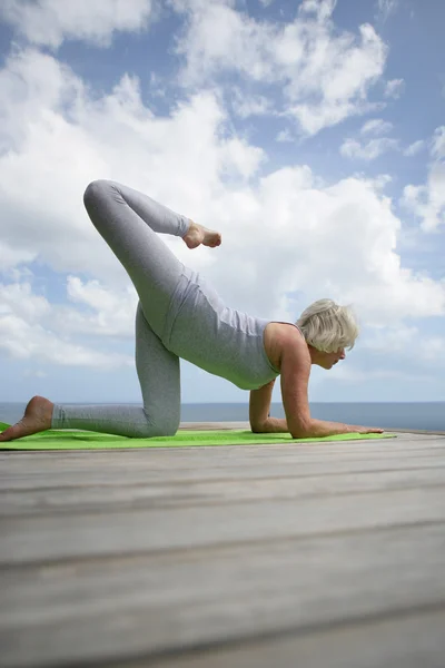 Woman practicing yoga by the ocean — Stock Photo, Image