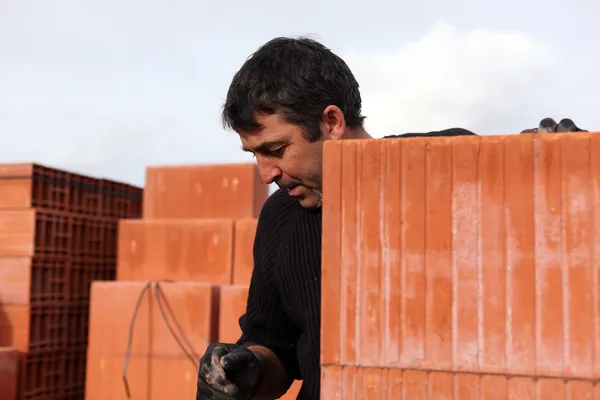 Housebuilder surrounded by large bricks — Stock Photo, Image