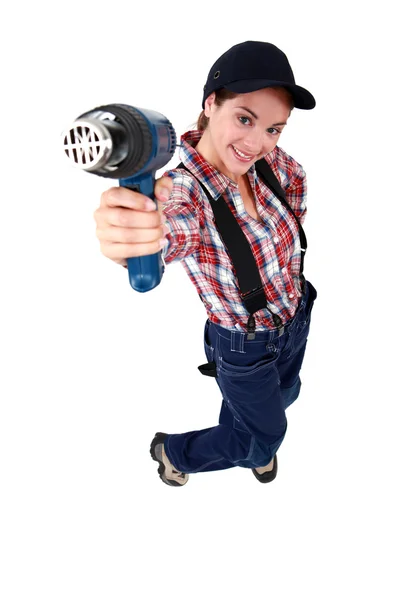 Tradeswoman holding up a heat gun Stock Photo