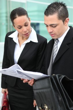 Business couple examining documents outside clipart