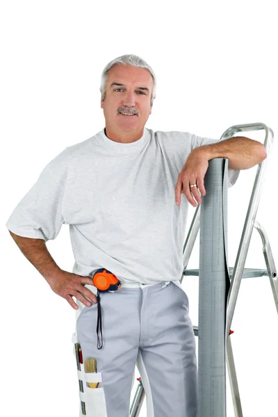 Middle-aged man with ladder and roll of wallpaper — Stockfoto