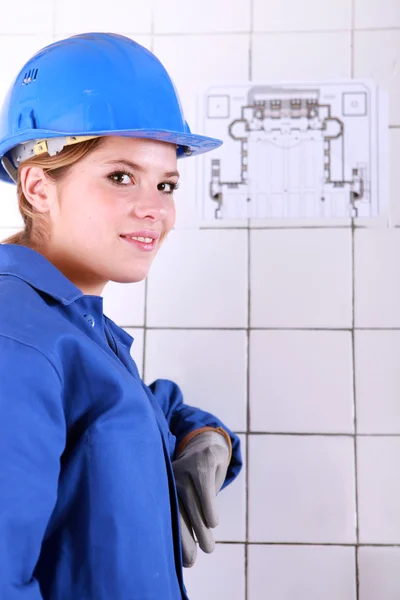 Young woman wearing a blue jumpsuite in front of an electrical schema — Stock Photo, Image