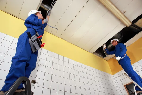Dos electricistas reparando el cableado del techo — Foto de Stock