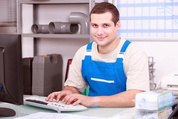 Bir bilgisayarda çalışan bir ofiste genç tesisatçı — Stok fotoğraf