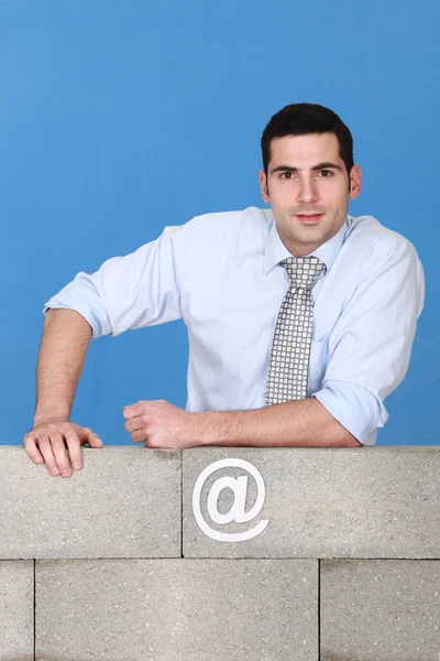 Arkitekt poserar med armen vilande på betongvägg — Stockfoto